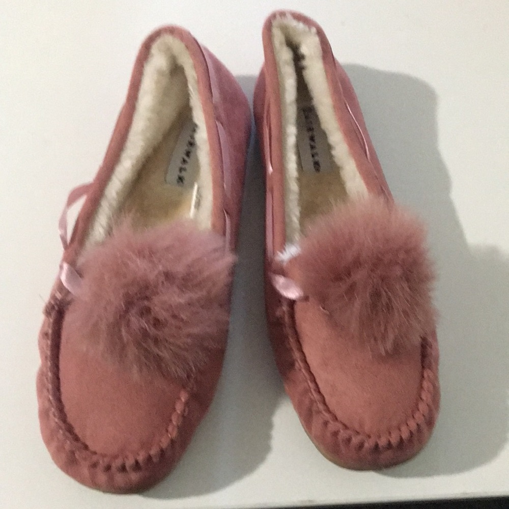 Women slip on moccasin with a decorative pom- pon.